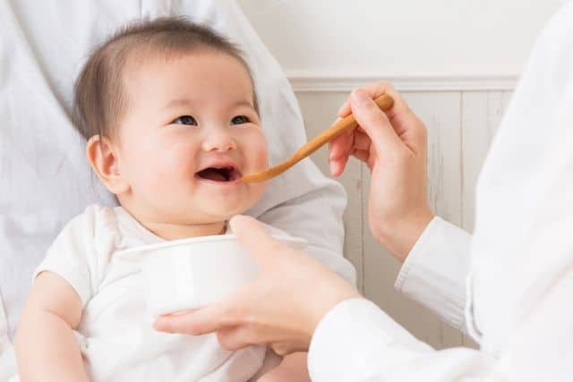 笑顔で離乳食を食べる赤ちゃん