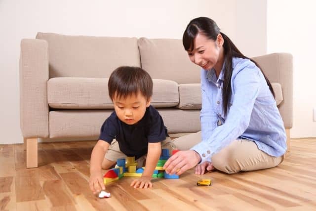 お母さんの隣で積み木をして遊ぶ男の子